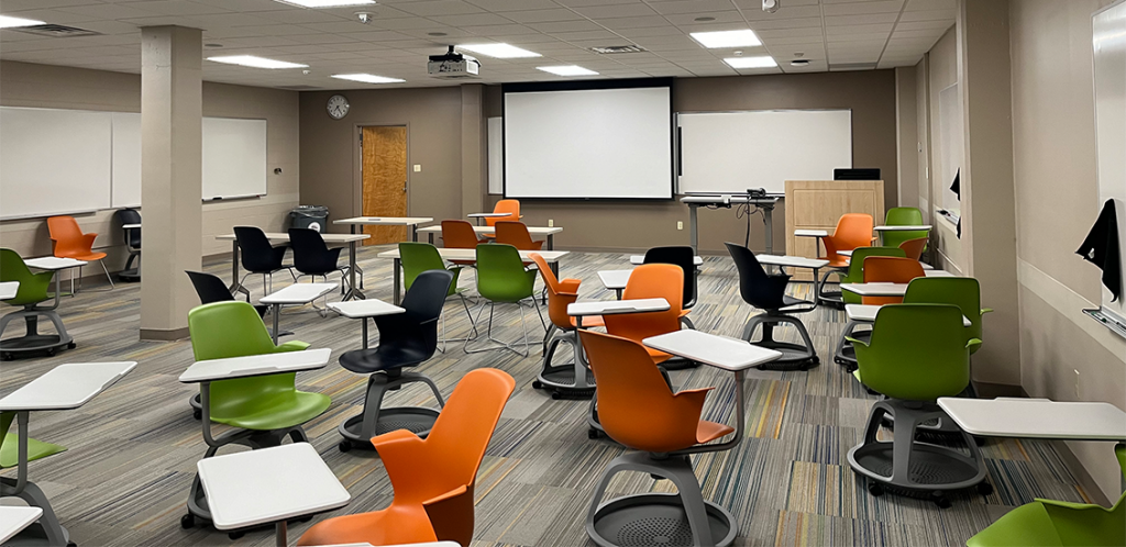 Health, Physical, Education, and Recreation 31A. Room includes individual desks and chairs that can be moved into different configurations. Instructor podium includes the control panel, instructor screen, and a spot for laptop. Next to the podium is a table that includes the document camera. The document camera table can be raised and lowered by pressing a button on the front of the table.