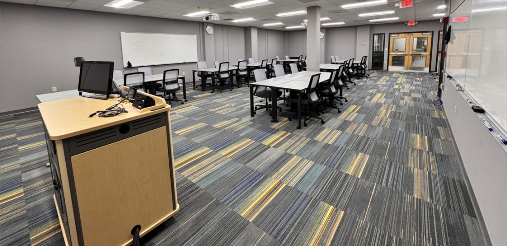 podium to left with tables and chairs for students