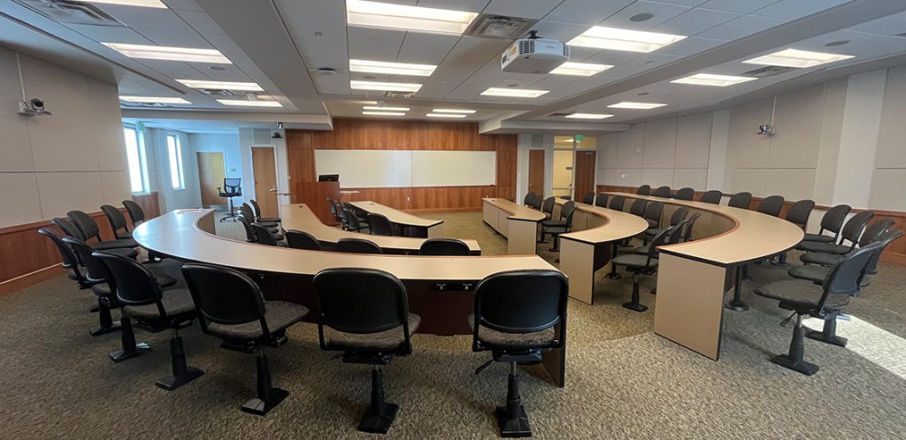 Haslam Business Building 403. Room includes amphitheater style seating. Instructor podium includes the control panel, instructor screen, and a spot for laptop.