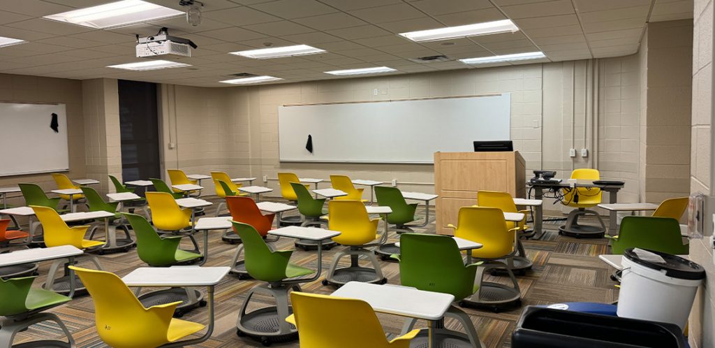 Humanities 53B. Room includes node chairs that can be moved into different configurations. Instructor podium includes the control panel, instructor screen, and a spot for laptop. Next to the podium is a table that includes the document camera. The document camera table can be raised and lowered by pressing a button on the front of the table.
