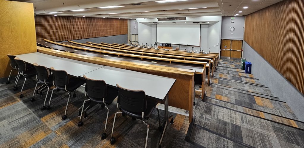 Stokely Management G4. Room includes theater style seating. Instructor podium includes the control panel, instructor screen, and a spot for laptop. Next to the podium is a table that includes the document camera.