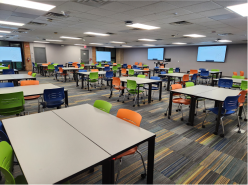 tables with chairs and several wall monitors on all walls